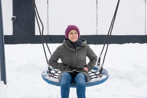 Woman smiling at the camera while seated on a blue rope swing Stock Photos