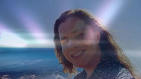 Woman smiling on coast light rays sweeping horizon crossing face causing head Stock Footage 333019087