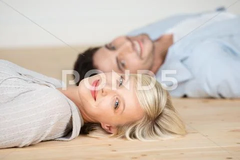 Woman smiling with man lying on hardwood floor Stock Photos