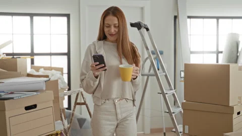 Woman smiling while checking smartphone and holding yellow mug amid stacked.. Stock Footage 339150340