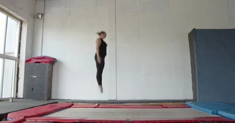 Woman is smiling while jumping on a trampoline and doing flips, 4k Stock Footage 158304204