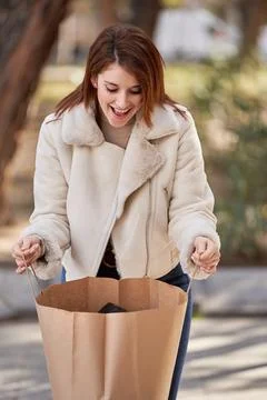 Woman smiling while looking inside her shopping bag outdoors. Fotos Stock