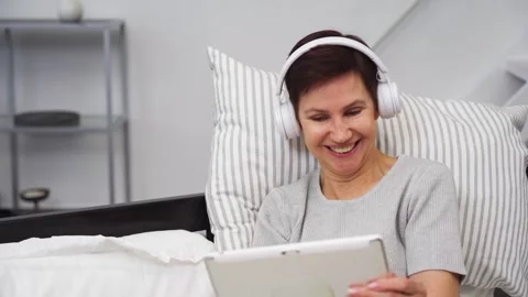 Woman smiling while looking at a tablet on headphones. Stock Footage 303762892