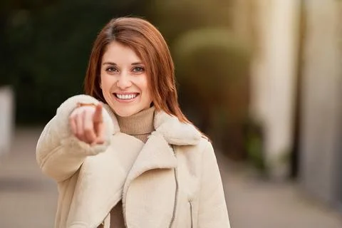 Woman smiling while pointing at the camera standing outdoors. Fotos Stock