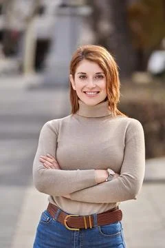 Woman smiling while posing with her arms crossed outdoors. 스톡 사진