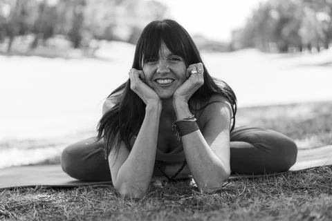 Woman smiling while resting in a comfortable yoga pose on the ground Stock Photos