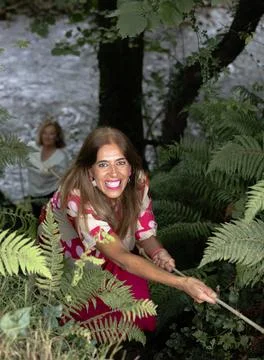 Woman smiling while sliding down with rope to river with friends Stock Photos