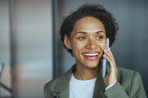 A woman is smiling while talking on a cell phone Stock Photos