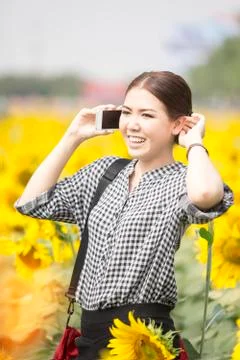 Woman smiling while using mobile phone in sunflowers field Foto stock