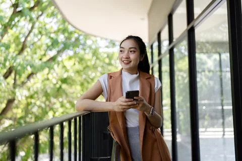 Woman smiling while using smartphone on balcony urban environment lifestyle Stock Photos