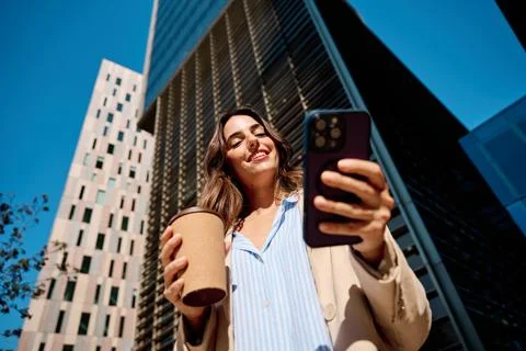 Woman smiling while video calling enjoying coffee in city Фото