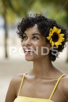 Woman smiling with yellow sunflower in her hair. Stock Photos