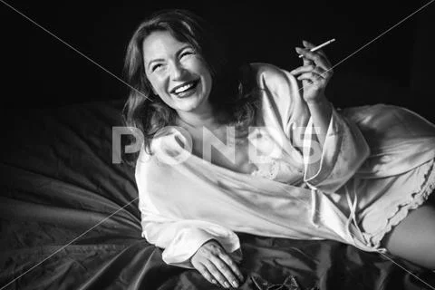 Woman smoking cigarette in bedroom, indoor Stock Photos