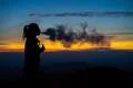 The woman smoking an electronic cigarette on the sunset background Photo