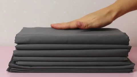 The woman smoothed a stack of folded sheets on the table with her hand Stock Footage 144325123