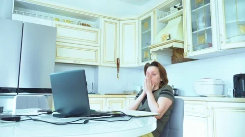 Woman sneezes while working at the computer while sitting at home in the kitchen Stock-Footage 148319605