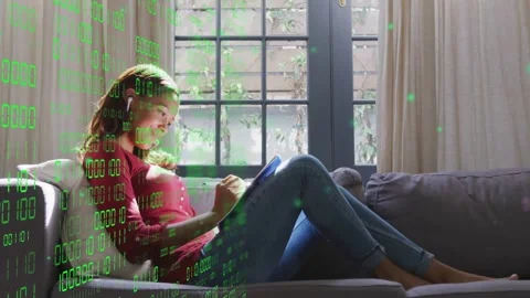 Woman on sofa using stylus, tapping tablet causing green code overlay drifting Stock Footage 333510079