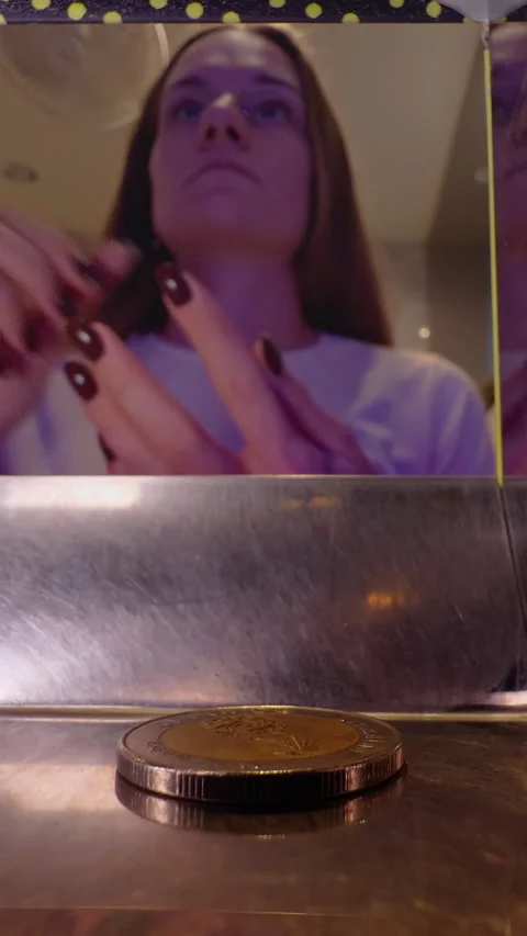 Woman in Soft Indoor Light Dropping Coins into Slot as Exchanged Coins Fall into Stock Footage 321294738