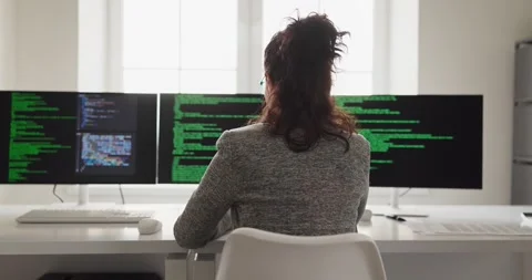 Woman software developer working on code across triple screens in office Stock Footage 333716481
