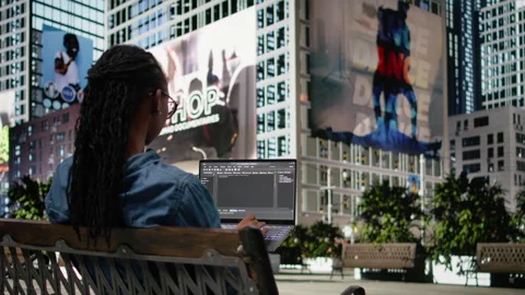 Woman software developer writing code on laptop and relaxing on park bench 動画素材 334169594