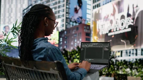 Woman software developer writing code on laptop and relaxing on park bench Stock Footage 334172365