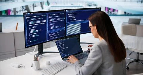 Woman Software Developer Writing Code On Laptop In Contemporary Workspace Stockfoto's