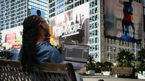 Woman software developer writing code on laptop and relaxing on park bench Photos