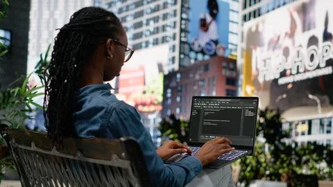 Woman software developer writing code on laptop and relaxing on park bench Foto stock