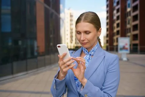 Woman solves her problems on phone against the backdrop of business building Stock Photos