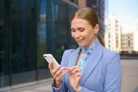 Woman solves her problems on phone against the backdrop of business building 库存照片