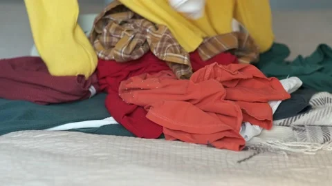 Woman sorting through pile of clothes, trying to declutter wardrobe Stock Footage 221897831