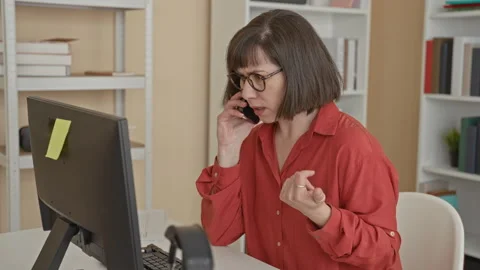 Woman speaking on smartphone at desk with computer and monitor, hand gestur.. Stock Footage 337419084