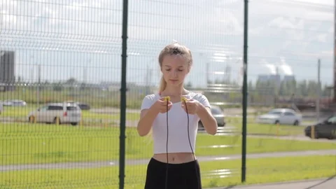 A woman in sport orange outfit jumps the rope in a street 1080p Stock Footage