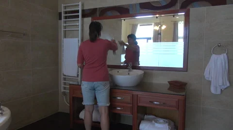 Woman spraying cleaning solution on bathroom mirror and wiping it with a rag Stock Footage 68387345