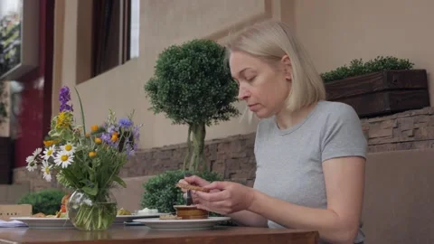 Woman spreading pate on bread while dining in a restaurant Stock Footage 133436117