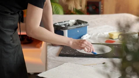 Woman spreading plaster paste on black canvas for abstract art Stock Footage 336947749