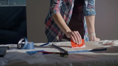 Woman spreading textured paste on white canvas using plastic scraper Video stock 332442086
