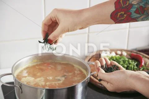Woman sprinkling ingredient into soup Stock Photos