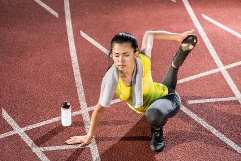 Woman sprinter doing warm up exercise before sprint Stock Photos