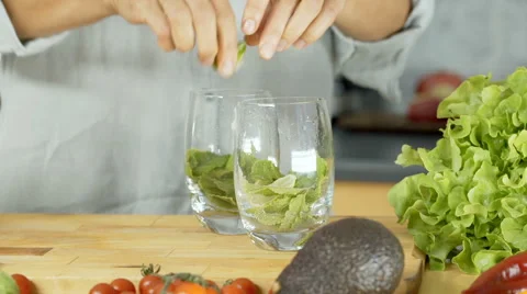 Woman squeezing lime into glasses while making a drink, dolly shot Stock Footage