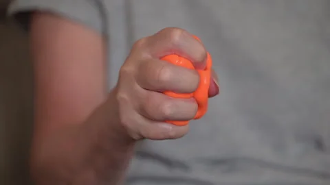 Woman Squeezing Orange Therapy Putty for Broken Arm Rehabilitation Stock Footage 345251374