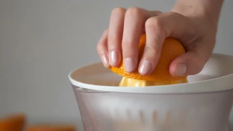 Woman is squeezing oranges using electric juicer in the kitchen, hand closeup. Stock Footage 158197234
