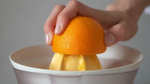 Woman is squeezing oranges using electric juicer in the kitchen, hand closeup. Stock Footage 159500280