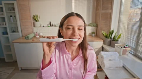 Woman Squeezing Toothpaste on Electric Toothbrush and Brushing Her Teeth Stock Footage 313507958