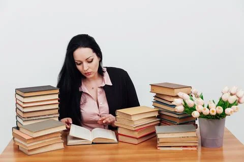 Woman with a stack of books in the library training science education Stock Photos