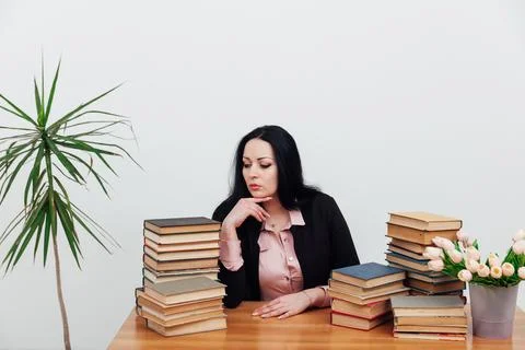 Woman with a stack of books in the library training science education Stock Photos