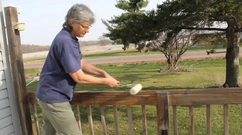 Woman staining a patio deck Stock Footage 62452259