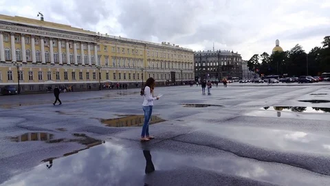 Woman stand between puddles at empty Palace Square, look up from city map Stock Footage 69946358