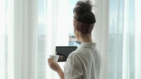 Woman stand at window at work with digital tablet and cup of coffee Video stock 242717769