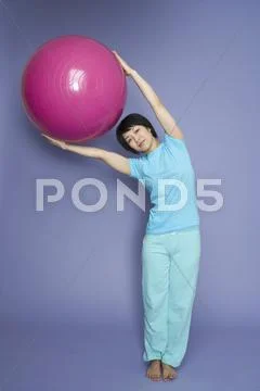 A woman standing and holding a fitness ball Stock Photos